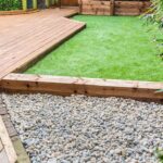 A section of a residntial garden, yard with wooden decking and .