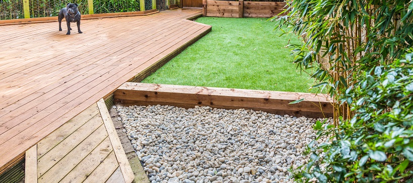 A section of a residntial garden, yard with wooden decking and .