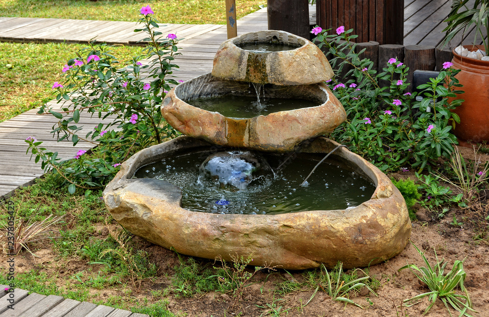 Small garden fountain with flowing water. Beautiful landscape .